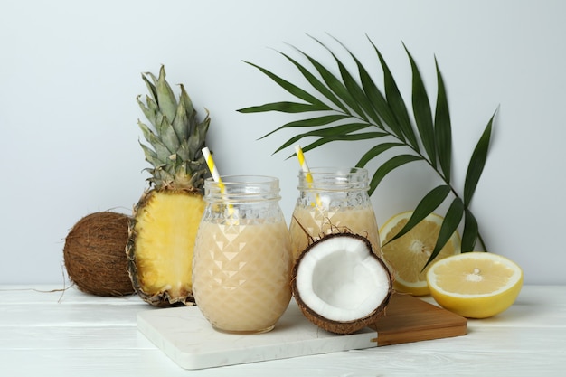 Pina colada cocktail e ingredienti sulla tavola di legno bianco.