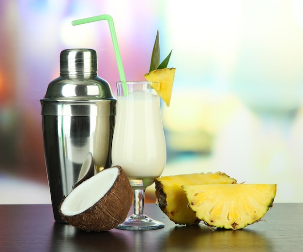 Pina colada drink in bicchiere da cocktail e shaker in metallo su sfondo luminoso