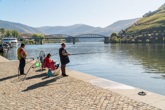 PINHAO REGIONE DEL DOURO PORTOGALLO 22 OTTOBRE 2017 persone che pescano su un lungofiume sul fiume Duoro nel villaggio di Pinhao Portogallo