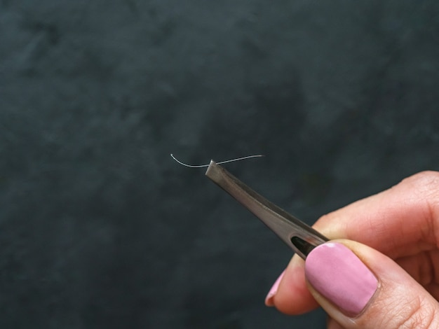 Pinzette con capelli bianchi su sfondo nero.