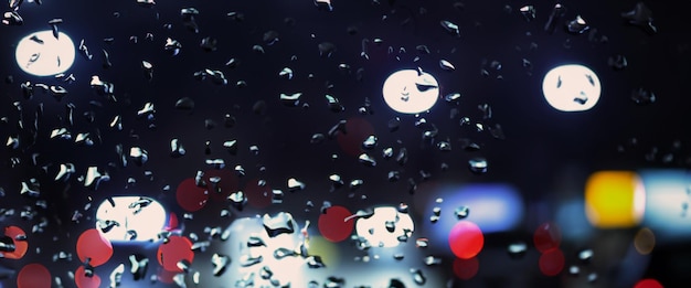 Pioggia sul finestrino dell'auto nella stagione delle piogge e strada sfocata sullo sfondo