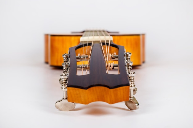 Pioli di sintonia su una testa di macchina in legno di una chitarra a sei corde su sfondo bianco