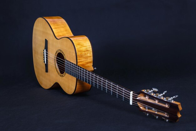 Pioli di sintonia sulla testa della macchina in legno del collo della chitarra acustica a sei corde su sfondo nero