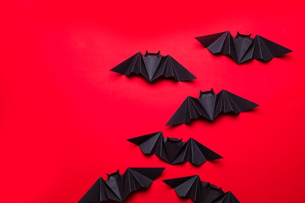 Pipistrelli di Halloween fatti di carta su sfondo rosso