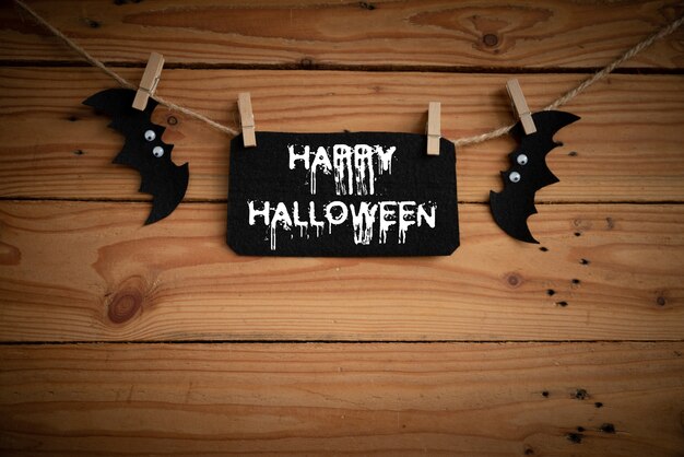 Pipistrello, ragno e ragnatela sul fondo della tavola in legno con testo Happy Halloween.