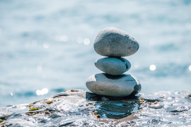 Piramide di ciottoli equilibrata sulla spiaggia in una giornata di sole mare astratto bokeh sullo sfondo selettivo