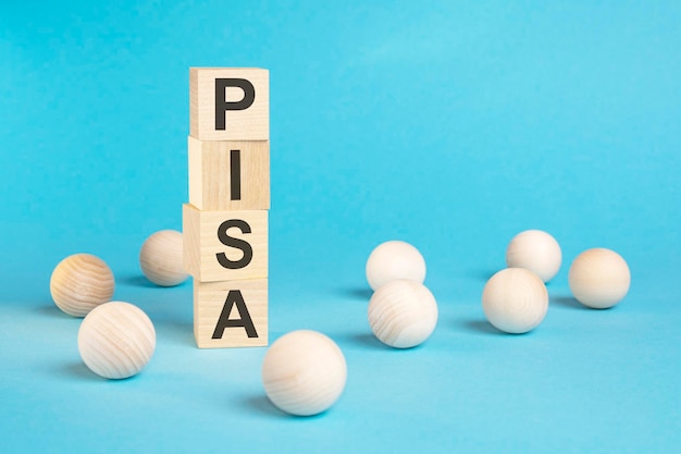 Piramide di cubi di legno con la scritta PISA e palline di legno su sfondo blu