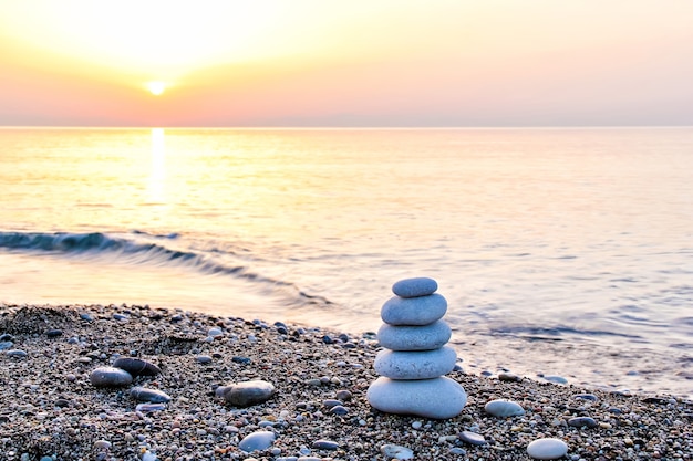 Piramide di pietra simile allo zen sulla spiaggia all'alba