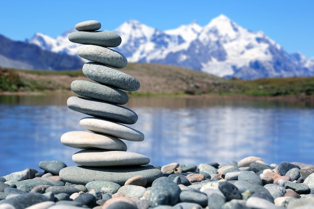 Piramide di pietre lisce sullo sfondo di un equilibrio naturale della vita di un lago di montagna