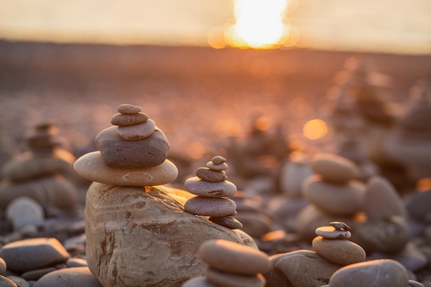 Piramide di pietre sul ciottolo che simboleggia l'armonia zen equilibrio oceano al tramonto sullo sfondo