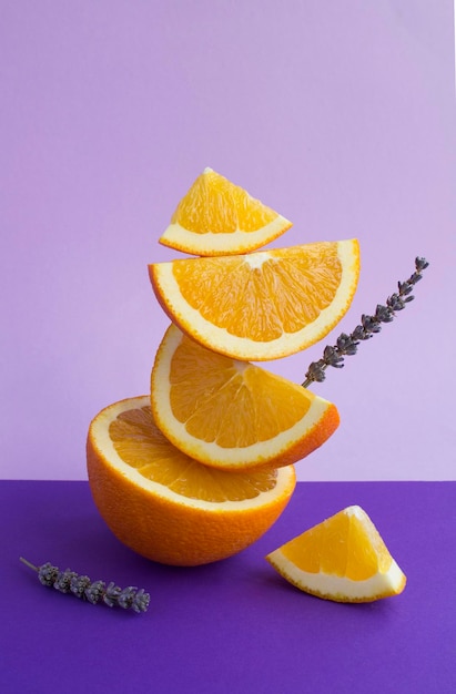 Piramide impilata di fiori di lavanda e frutta arancione sullo sfondo viola. Primo piano.