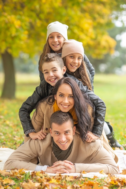 Piramide umana di cinque membri sdraiati della famiglia all'aperto in una giornata autunnale.