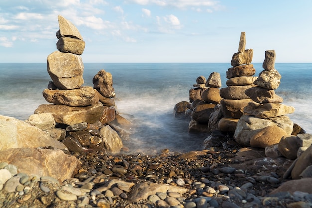 Piramidi di pietre di mare in riva al mare. Ingresso al mare.