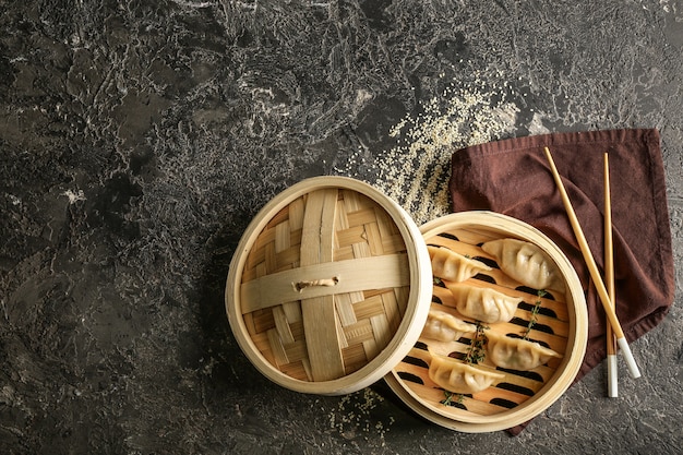 Piroscafo di bambù con gustosi gyoza giapponesi sul tavolo del grunge