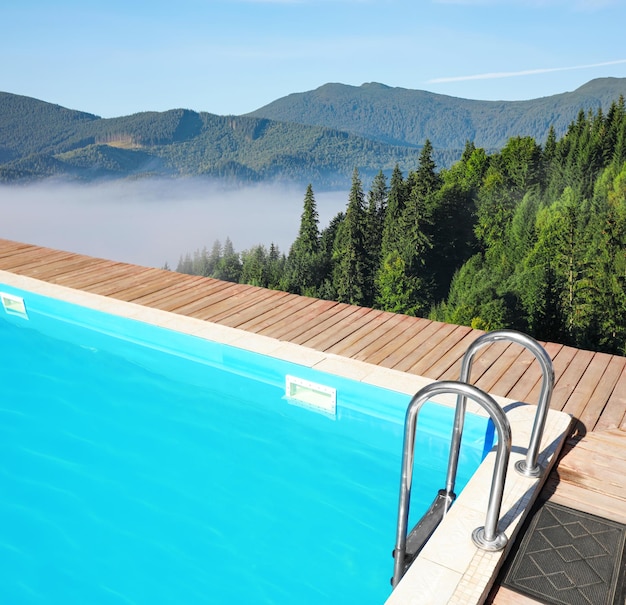 Piscina all'aperto presso resort di lusso e splendida vista sulle montagne in una giornata di sole
