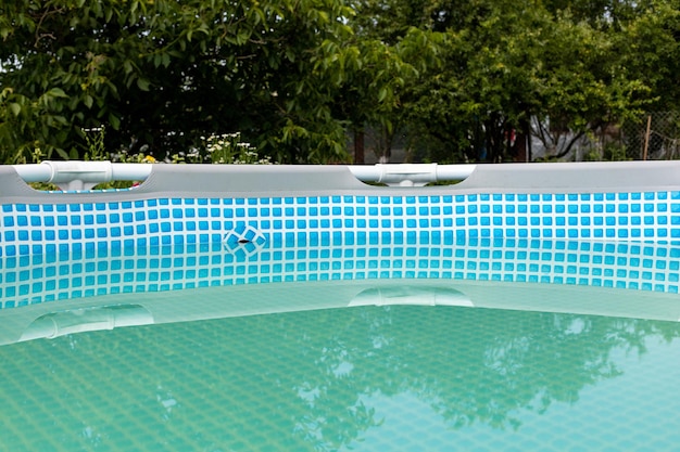 Piscina con cornice grigia sul prato verde con alberi