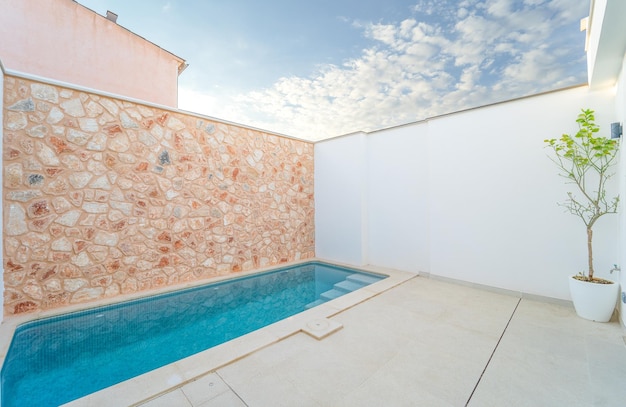 Piscina con parete in pietra bianca e naturale in terrazza