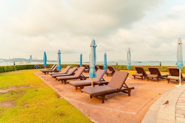 Piscina con sedia o piscina per lettino e ombrellone intorno alla piscina con sfondo di spiaggia del mare a Pattaya in Thailandia