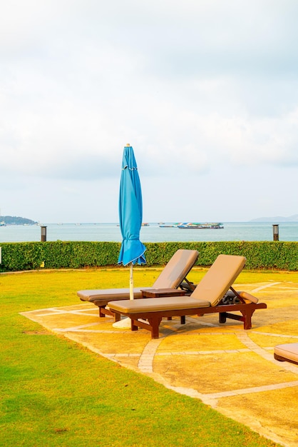 Piscina con sedia o piscina per lettino e ombrellone intorno alla piscina con sfondo di spiaggia del mare a Pattaya in Thailandia