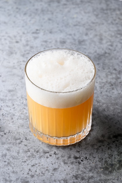 Pisco sour cocktail. Whisky con lime, albume d'uovo, sciroppo in vetro su grigio.