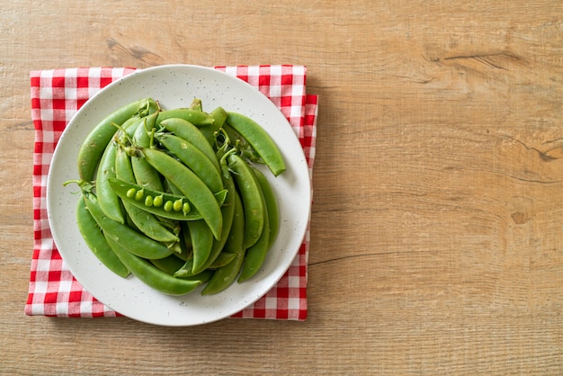 piselli freschi dolci verdi sulla piastra bianca