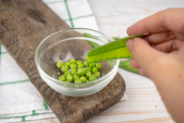 Pisello verde crudo in una ciotola di vetro sul bordo di legno