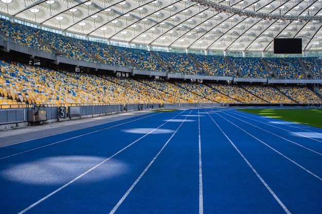Pista da corsa blu vuota allo stadio olimpico sullo sfondo di tribune vuote