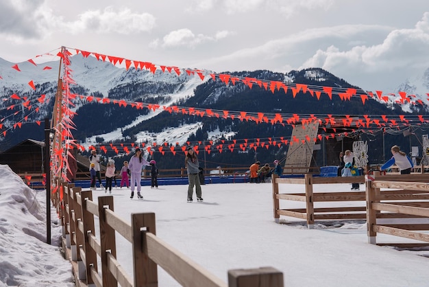 Pista di pattinaggio su ghiaccio all'aperto con bandiere rosse e vista sulla montagna in scena invernale