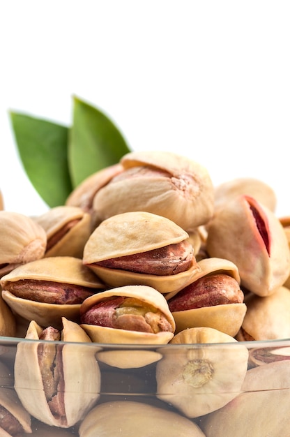 Pistacchi in ciotola di vetro su bianco