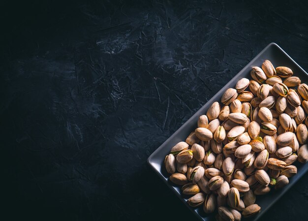 Pistacchi in un piatto rettangolare grigio su un tavolo scuro