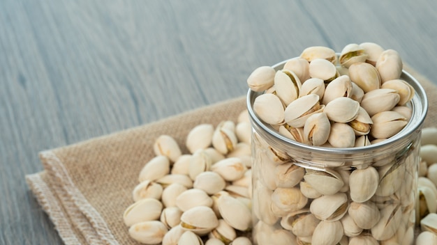 Pistacchi in vaso di vetro trasparente su un tavolo di legno. Cibo sano ad alto contenuto proteico.