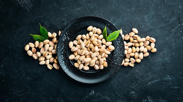 Pistacchi salati in una ciotola su sfondo nero Vista dall'alto Spazio libero per il testo