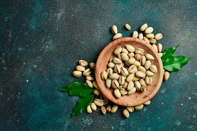 Pistacchi tostati e salati in una ciotola di legno Vista superiore Spazio libero per la copia