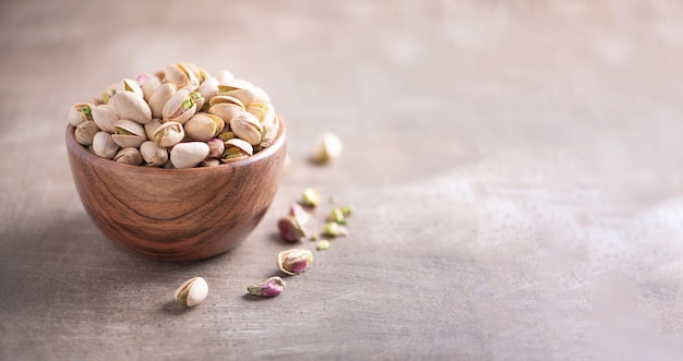 Pistacchi verdi in ciotola di legno su sfondo strutturato in legno Copia spazio Superfood vegan concetto di cibo vegetariano Macro di pistacchio texture fuoco selettivo Spuntino sano