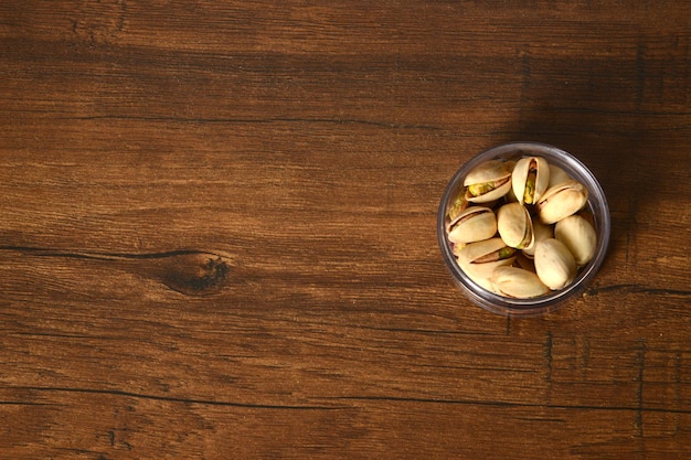 Pistacchio fresco nella ciotola di legno, organico, fondo bianco del bordo, fondo di legno.