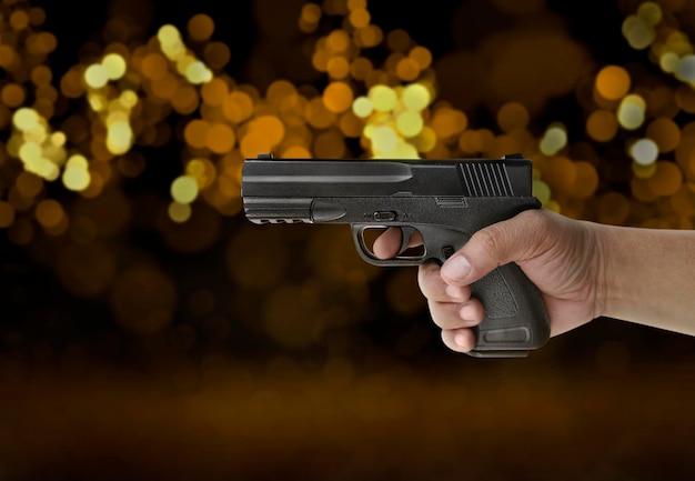 Pistola maschio della tenuta della mano sul bokeh della luce di notte del fondo in città