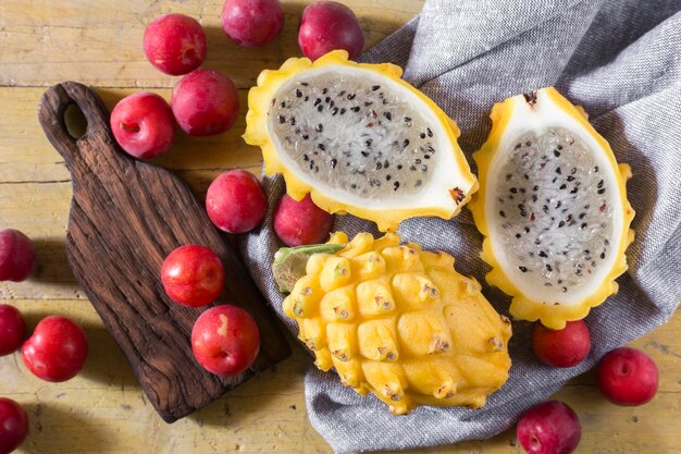 Pitahaya giallo o frutta del drago e prugna rossa su fondo di legno