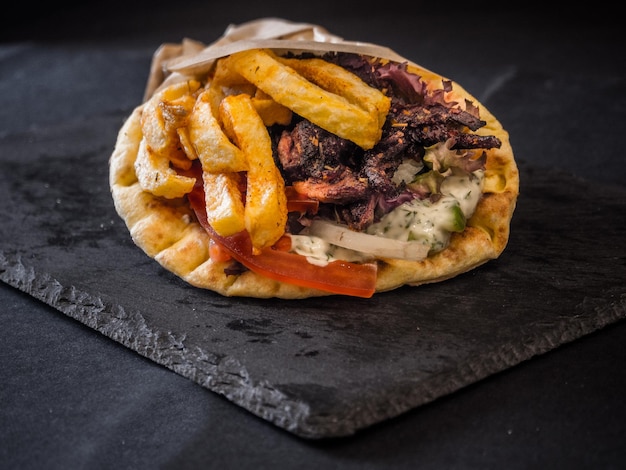 Pitta vegana al legno servita con patate fritte, cipolla, pomodoro e spezie