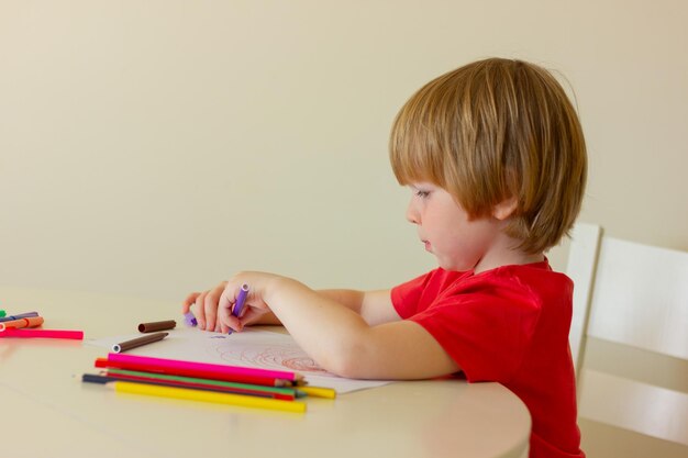 Pittore bambino ragazzo con matite colorate mentre seduto atable sviluppo infanzia educazione tempo libero