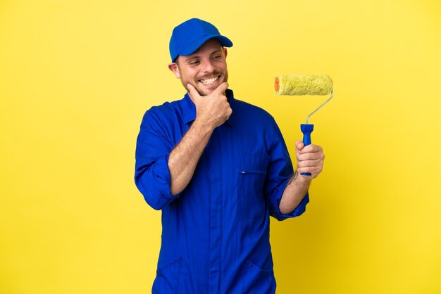 Pittore brasiliano uomo isolato su sfondo giallo guardando di lato e sorridente