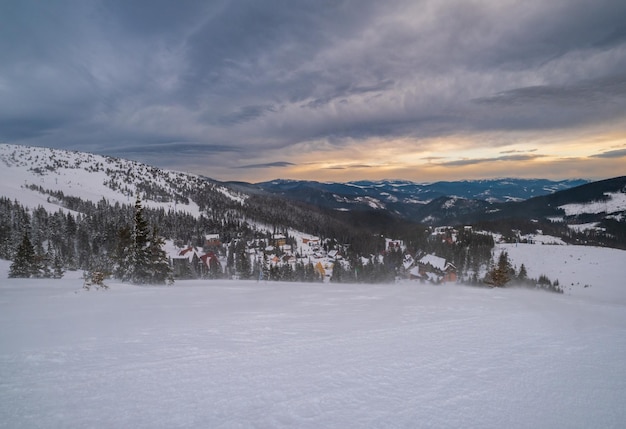 Pittoresche Alpi mattutine ventose e nuvolose invernali Vista della famosa località sciistica ucraina di Dragobrat dalla cresta della montagna di Svydovets
