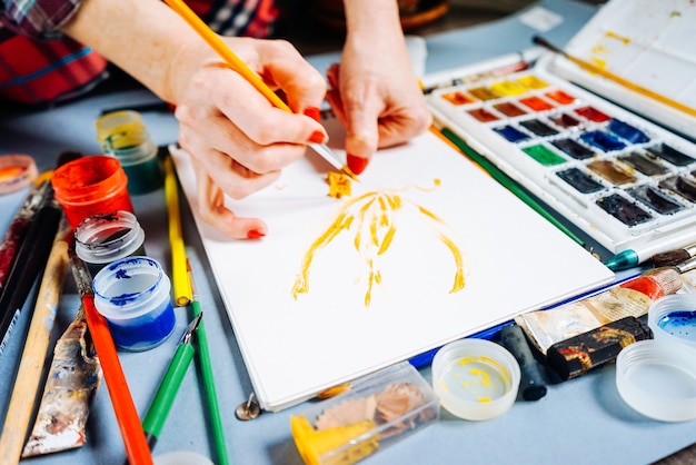 Pittrice dipinge con colori vivaci e pennello su carta bianca