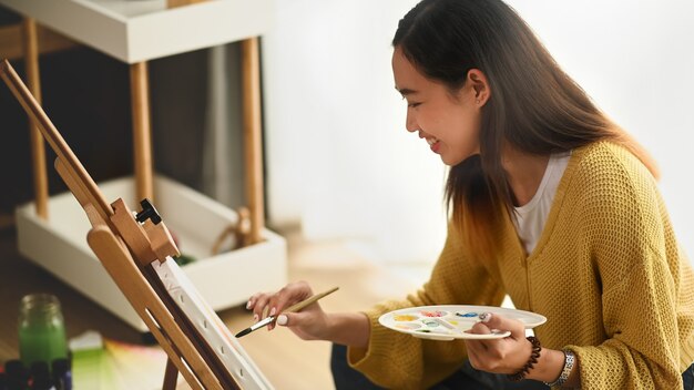 Pittura della giovane donna su una tela a casa