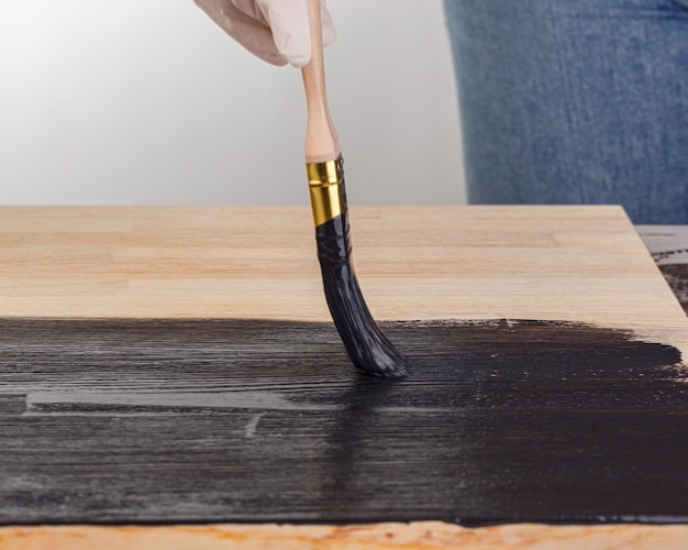 Pittura fondo in legno a mano con pennello e barattolo di vernice