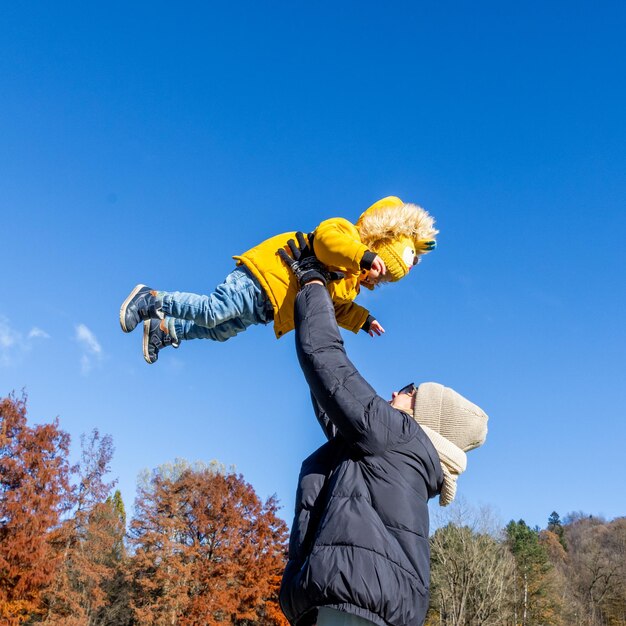 Più più mamma che è divertente felice giovane madre lancia il suo bambino carino in aria giorno della madre