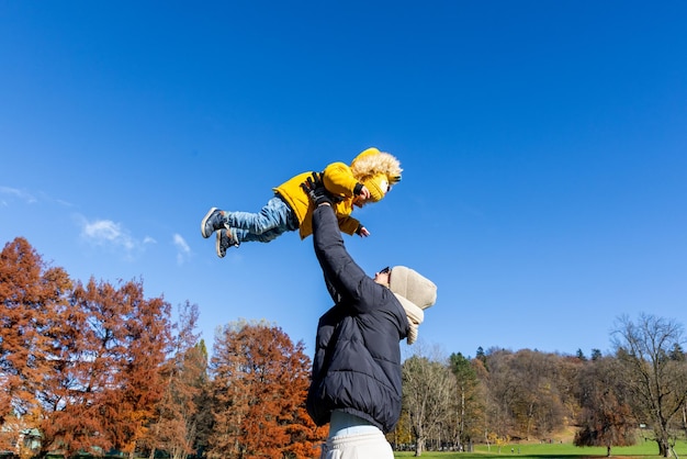 Più più mamma che è divertente felice giovane madre lancia il suo bambino carino in aria giorno della madre