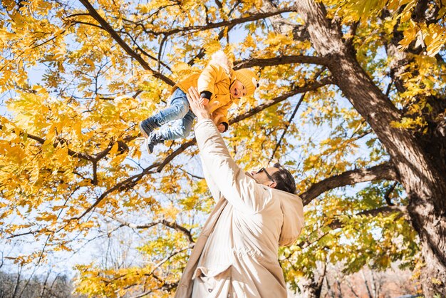 Più più papà che è divertente felice giovane padre lancia il suo carino piccolo bambino felice in aria