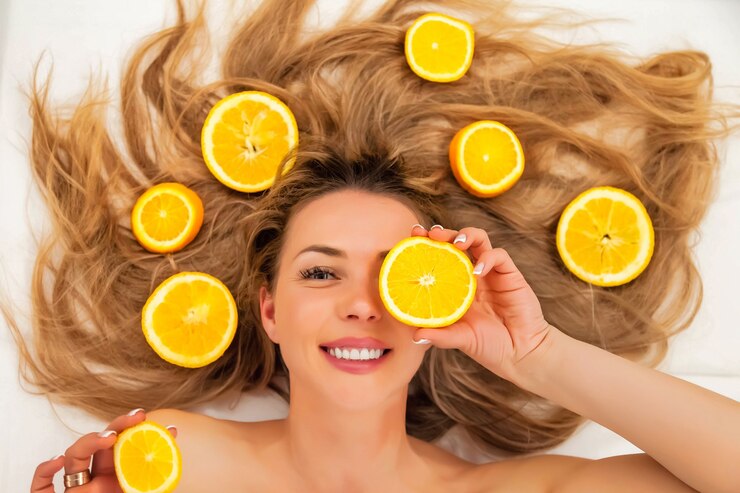 Piuttosto affascinante gioiosa attraente allegra giovane donna positiva con i capelli lunghi con pezzi di arancia, chiudere un occhio su sfondo bianco. Concetto di bellezza, salute e cura del corpo personale. Copia spazio