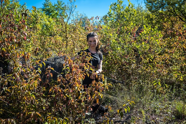 Piuttosto cacciatore femminile in cima nella foresta con arma in natura selvaggia. stile di vita