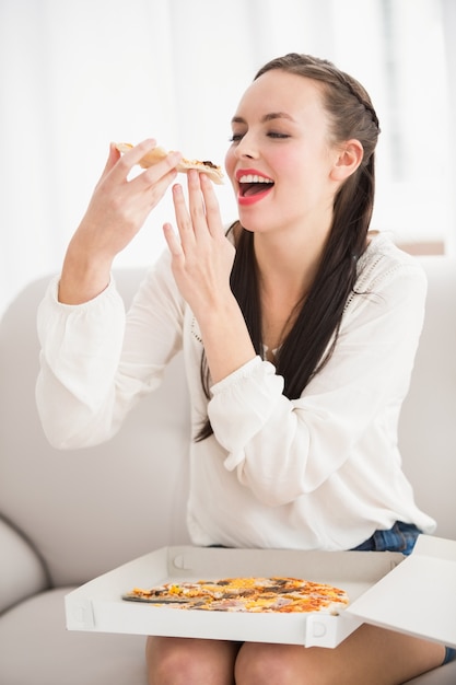 Piuttosto castana che mangia fetta di pizza